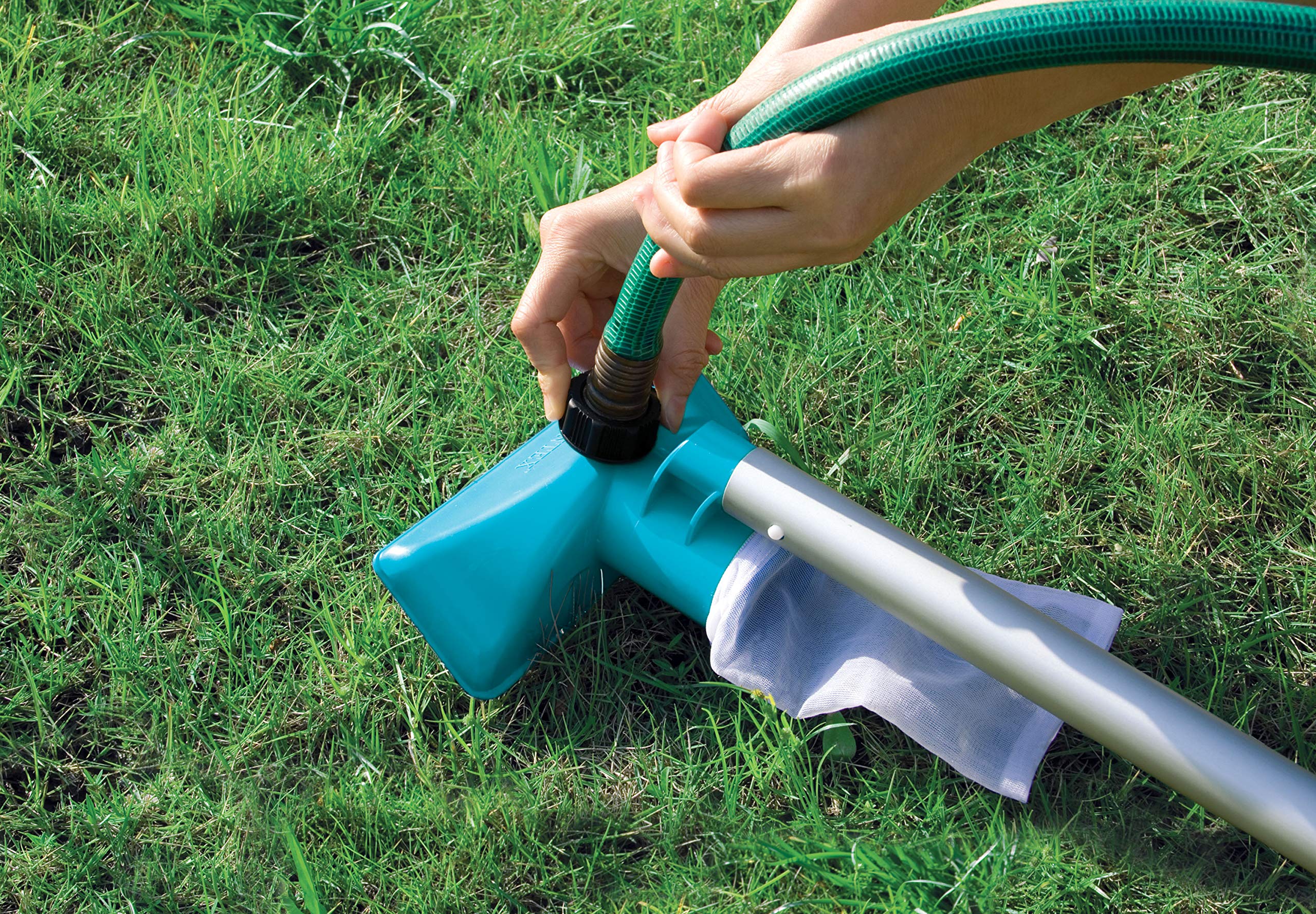 Hands connecting a garden hose to the teal Intex vacuum head on grass