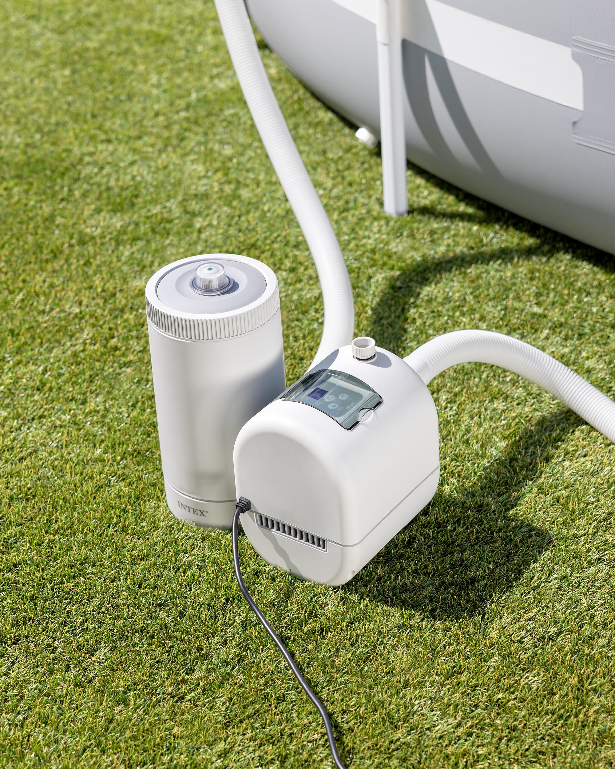 Intex C2500 pump and filter canister connected by a hose and set up on grass beside an above-ground pool